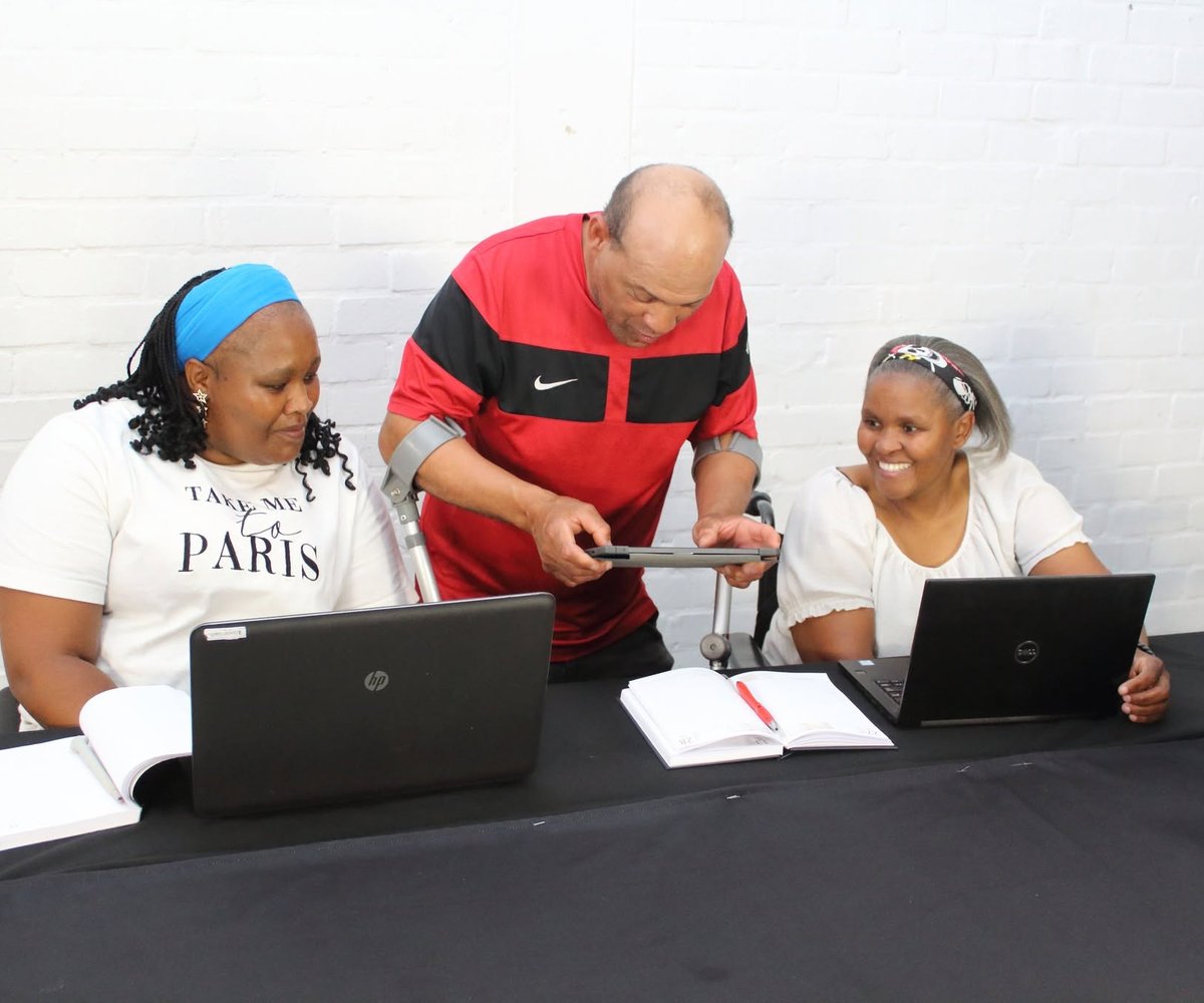 A member who uses a wheelchair working at a laptop with support staff